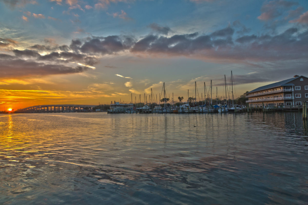 Sunset overlooking Cocoa Village Dentistry Office and the marina at Mariner Square with boats at the dock and a bridge